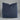 Blue pillow on a white surface with a visible tag.