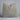 Textured gray pillow on a light gray surface with a neutral background