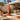 Original Modfire orange wood-burning outdoor fireplace in a sunny mid-century modern California patio with white breeze-block wall and coordinating outdoor furniture.