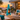 Turquoise Original Modfire wood-burning fireplace with visible flames on a coastal modern patio overlooking the ocean at sunset.