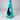 Front studio view of the Original Modfire turquoise wood-burning outdoor fireplace, featuring a tapered metal body and signature teardrop firebox opening.